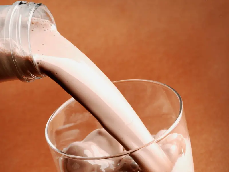 A chocolate milk brand being poured into a glass.